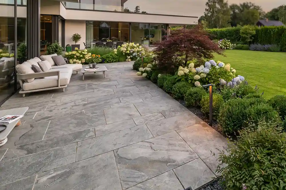 Natursteinterrasse mit Sitzgruppe und Blockstufe an einer Berliner Stadtvilla – Terrassenbau Berlin von Berliner Galabau